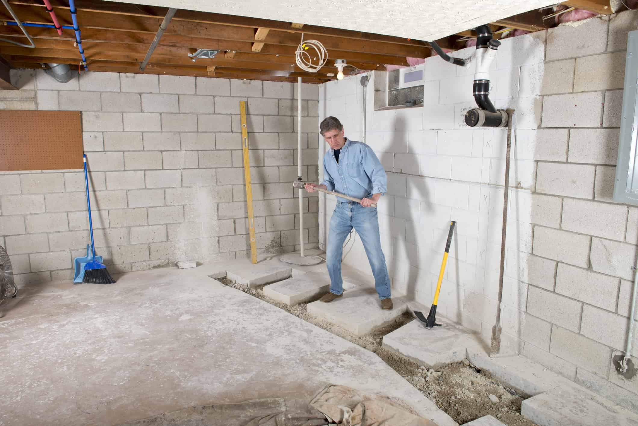 man in basement removing cement floor